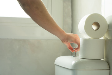 Mano tirando de la cadena en cuarto de baño blanco con luz natural. 