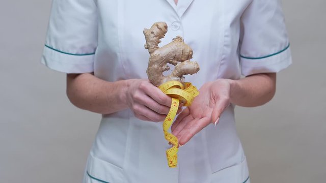 nutritionist doctor healthy lifestyle concept - holding ginger root and measuring tape