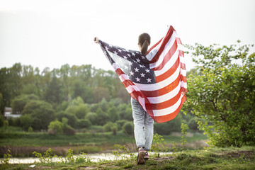 A young woman in nature with an American flag.