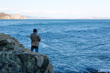 Fototapeta na wymiar Fisherman catches fish from the rocks