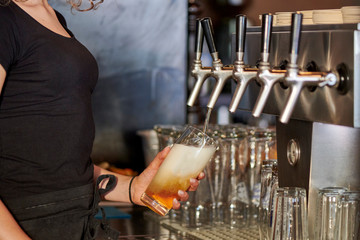 Junge Barfrau zapft hinter der Bar ein glas Bier Getränk im bayrischen Wirtshaus Biergarten