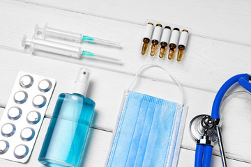 Medical equipment. Stethoscope, mask and pills on white wooden desk close up