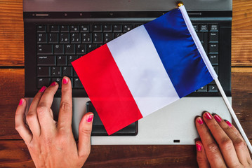 woman hands and flag of France on computer, laptop keyboard