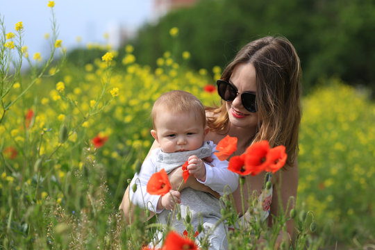 mom with a child have fun playing in a flower field and grass in the sun in a park