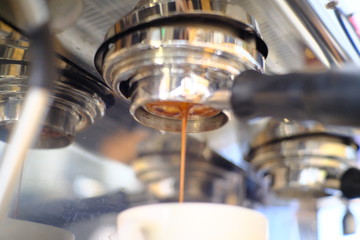 Espresso poruing from coffee machine at cafe
