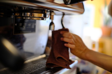 barista woman cleaning professional coffee machine with dust
