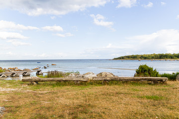 An empty deserted calm sandy beach on a sunny day with wooden benches