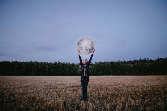 girl in a field holding a moon