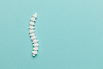 Spine with pills on a blue background. Back pain and treatment. Inflammation in the lower back.