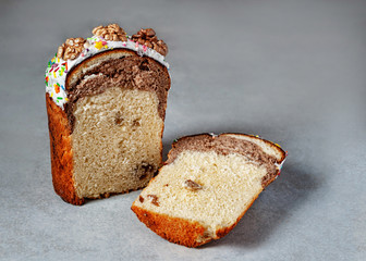 Sliced ​​marble muffin with cocoa on a gray background. Sweet Marble Raisin Bread. Baking decorated with icing and walnuts. Selective focus