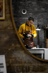 A young man is engaged in Shoe repair. Shoe workshop. The photo illustrates a small business