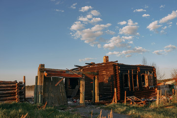 Fototapeta premium A burned-out tree house on a Sunny day in the village. Ruins and debris of a house against a blue sky with clouds. | KOROVYAKOVA, SVERDLOVSKAYA OBLAST - 9 MAY 2020.
