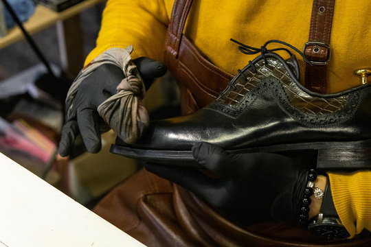 A young man is engaged in Shoe repair. Shoe workshop. The photo illustrates a small business