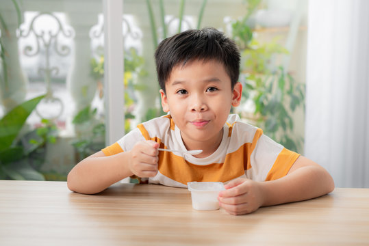Portrait of smiling little boy eating delicious yogurt