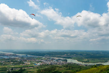 Outdoor city green hill scenery and paragliding