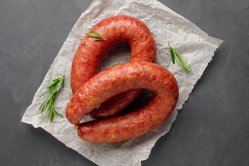 Smoked sausage with rosemary on a black slate background. Top view. Flat lay. - obrazy, fototapety, plakaty