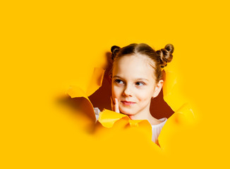Face of little girl peeping out of hole in a wall