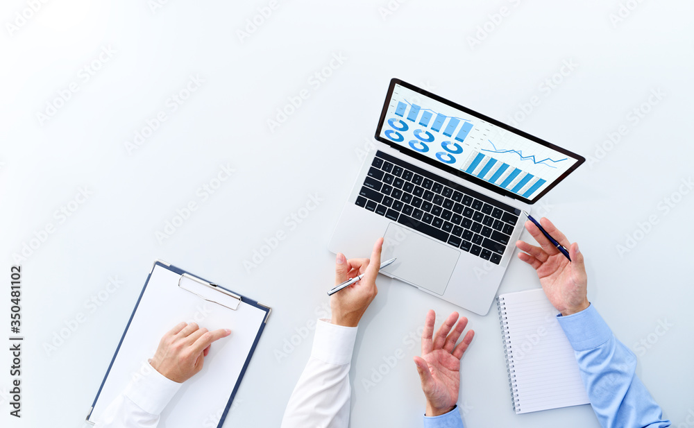Poster top view of business meeting. two men discussing. graphs and charts on laptop screen.
