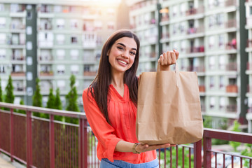Express grocery delivery service. Smiling young woman looking at camera holding eco bag deliver...