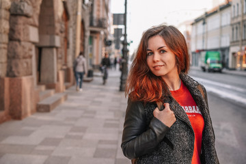 Fototapeta premium A young girl in a jacket walks through the streets of the city, portrait against the background of a beautiful old building, business style