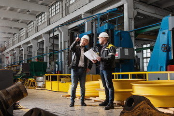 Two young engineers at a modern factory. The photo illustrates new technologies and production.