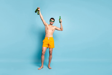 Full length body size photo of cheerful positive handsome man smile toothy raising few bottles of beer bringing them to friends isolated pastel blue color background