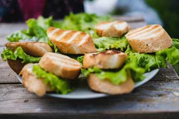 vegetarian sandwiches with vegetables and lettuce leaves are placed on a round white plate. white bread bruschetta or grilled baguette