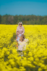 Happy family of three together at meadow outdoor. Bright Yellow rapeseed oil.