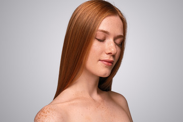 Redhead woman with freckled skin and closed eyes