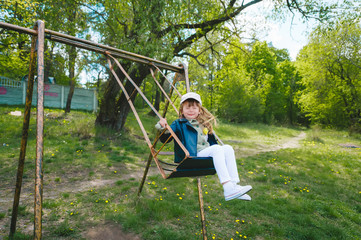 Cute preschool laughing girl swinging on a swing at the playground.