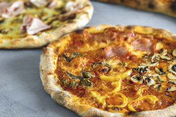 baked pizza with anchovies, tomato sauce, salami, bell pepper, topped with melted cheese, on a wooden table, on a background of baking