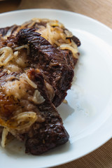 beef and onion baked in foil is on a white plate