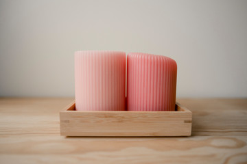 the theme of the Spa. thick pink aroma candles stand on a stand made of natural wood on a wooden table