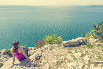 Active woman sitting and enjoying sea view. Living life and meditating.