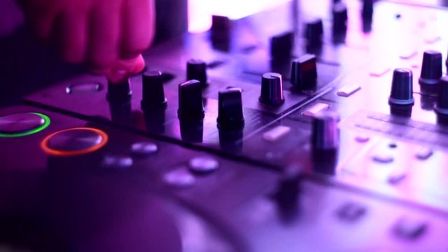 DJ adjusts the sound settings on the remote in a nightclub, disco, equalizer, slow motion