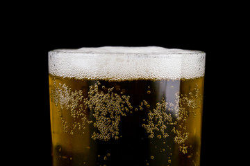 A glass of beer isolated on a black background close-up.