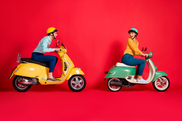 Fototapeta na wymiar Profile side view of her she his he nice attractive positive cheerful cheery couple riding moped having fun time fast speed racing isolated on bright vivid shine vibrant red color background