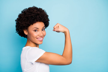 Fototapeta na wymiar Closeup profile photo of beautiful dark skin curly lady showing perfect shape biceps after intense training gym wear casual white t-shirt isolated blue color background