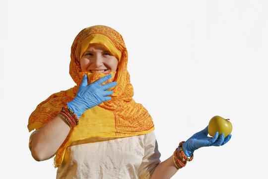 Portrait of the girl in Indian dress and blue protective gloves with an yellow apple