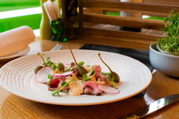 Beef carpaccio on white plate with mustard parmesan