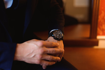 Male businessman dresses and adjusts his watch, preparing for a meeting. Clock