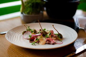 Beef carpaccio on white plate with mustard parmesan