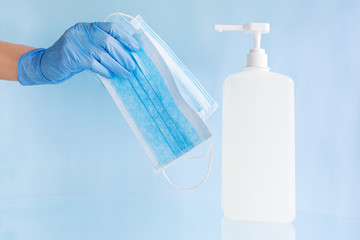 Medical face masks, surgical protective disposable face mask in doctor hand in blue gloves. Bottle...
