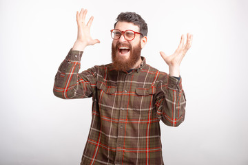 Fototapeta premium Excited man is screaming with eyes closed and hands in the air on white background.