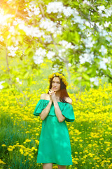 beautiful girl enjoys spring with a wreath of dandelions on her head