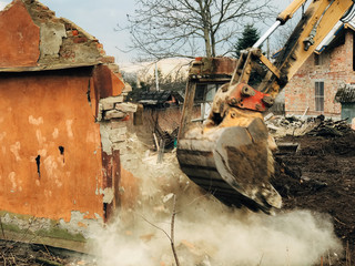 House crushing and collapse. Excavator destroying brick house on land in countryside. Bulldozer...