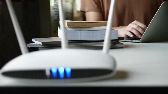 Close up of a wireless router and a man using laptop on the table.