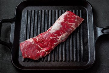 Raw machete steak on beef in a grill pan. Stone background.