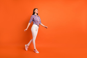 Fototapeta na wymiar Full length body size view of nice attractive lovely slender cheerful dreamy straight-haired girl wearing checked shirt walking enjoying isolated on bright vivid shine vibrant orange color background