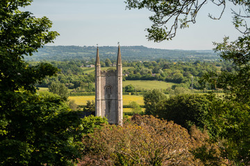 Naklejka premium The tower of St Michael's church in Mere, Wiltshire framed by trees, leaves and foliage. Wiltshire somerset border uk countryside landscape scene.